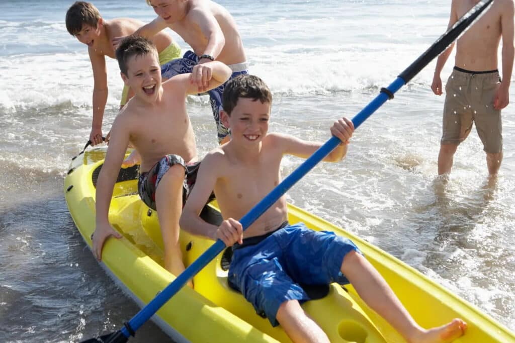 Kids enjoy kayaking and beach fun together, highlighted in a family-friendly digital area guide.